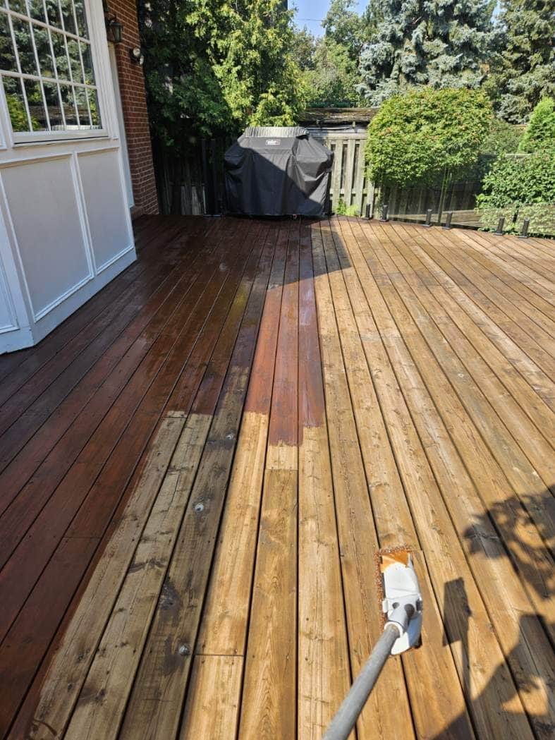 Deck mid-job: bare washed boards on the right, freshly stained boards on the left