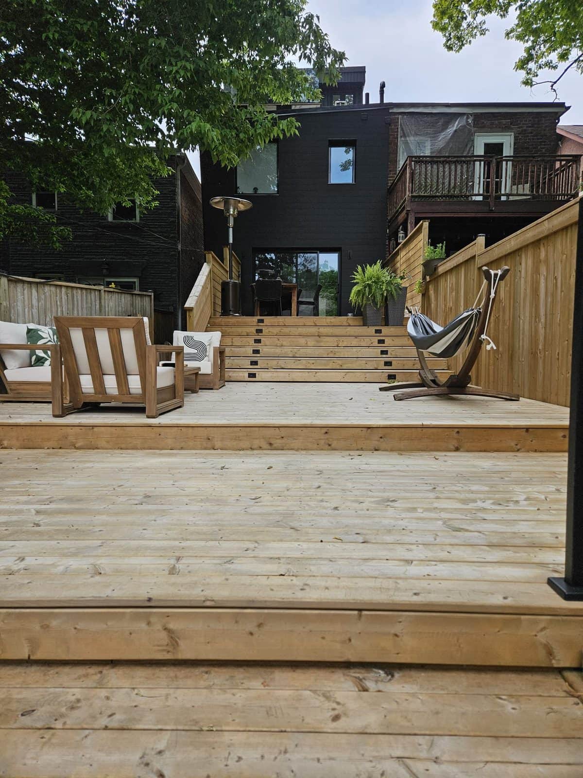 Two-level pressure-treated deck with wide stairs leading up to a black house