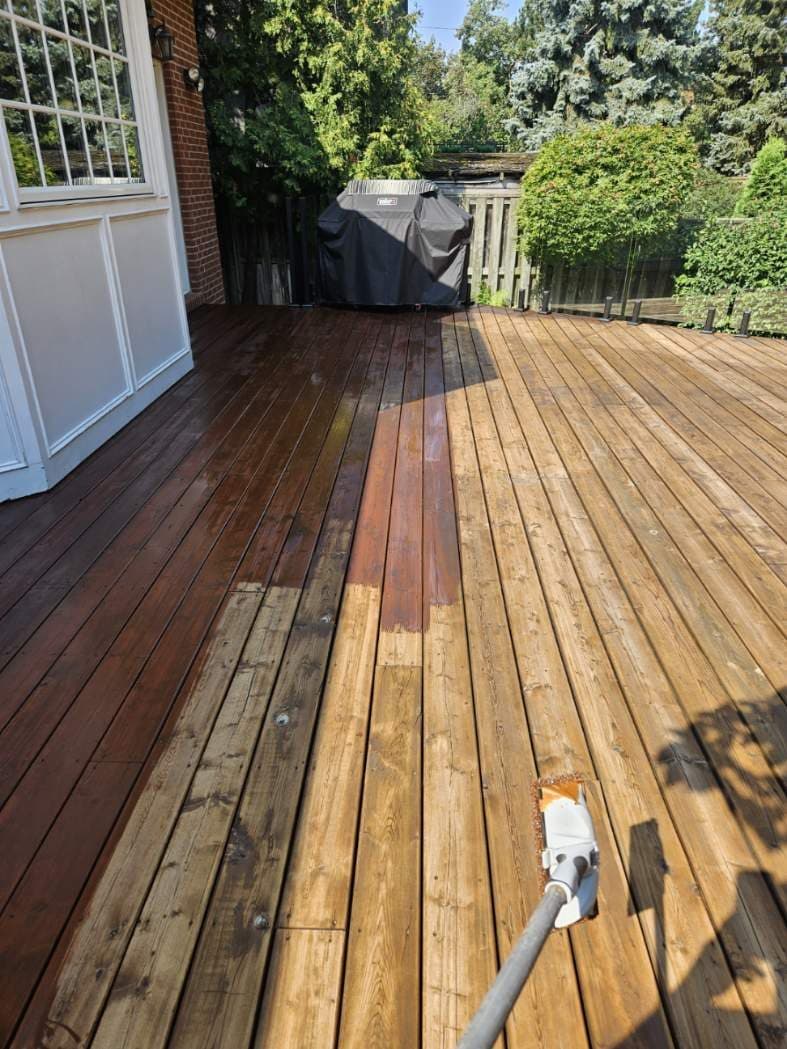 Deck mid-job: bare washed boards on the right, freshly stained boards on the left