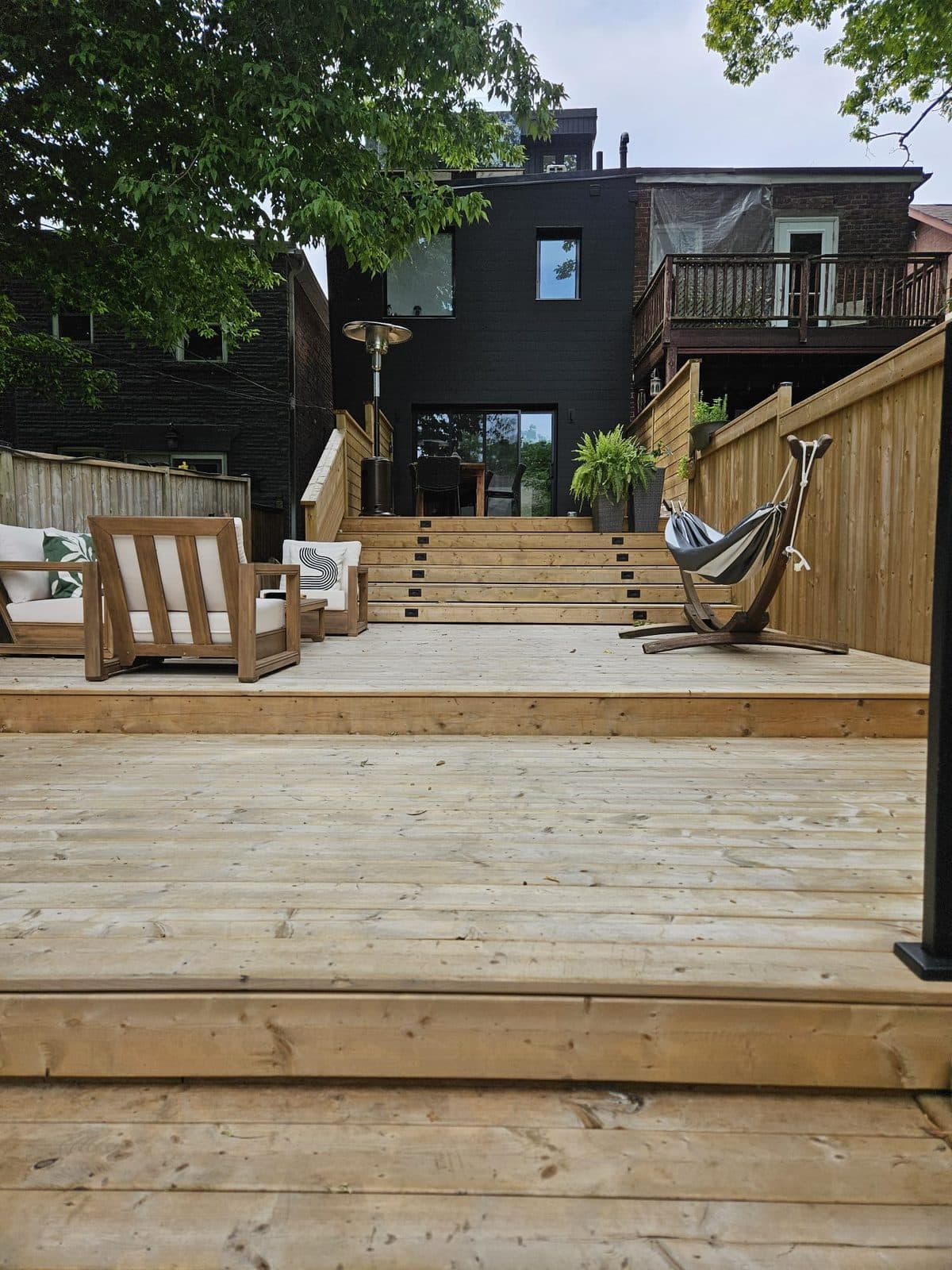 Two-level pressure-treated deck with wide stairs leading up to a black house